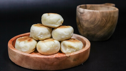 Bakpia Jogja, Bakpia Pathok is a typical Yogyakarta food made from a mixture of green beans, which is wrapped in flour, then baked. Selective focus. Served in wooden plate. Isolated Black Background.