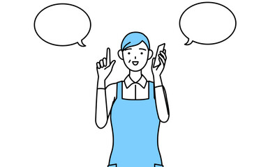 電話をしながら指さしをするエプロンを着たシニア女性