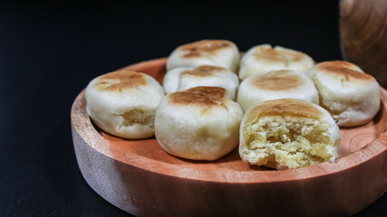 Bakpia Jogja, Bakpia Pathok is a typical Yogyakarta food made from a mixture of green beans, which is wrapped in flour, then baked. Selective focus. Served in wooden plate. Isolated Black Background.