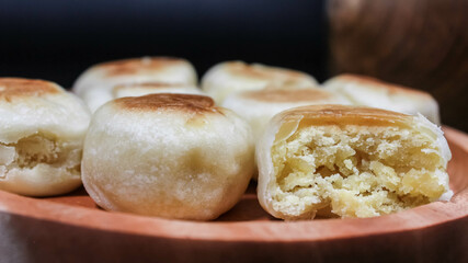 Bakpia Jogja, Bakpia Pathok is a typical Yogyakarta food made from a mixture of green beans, which is wrapped in flour, then baked. Selective focus. Served in wooden plate. Isolated Black Background.