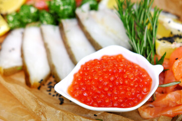 Fillet mix of red and white fish cut into slices with oil, red caviar and lemon, restaurant serving
