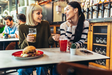 Smiling young friends drinking craft beer in pub