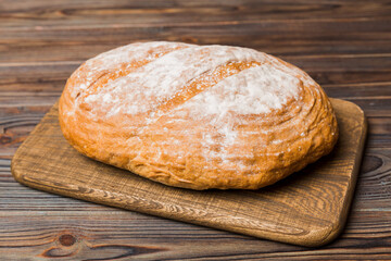 Freshly baked bread on cutting board against white wooden background. perspective view bread with copy space