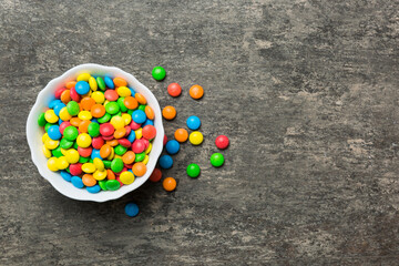 Multicolored candies in a bowl on a colored background. birthday and holiday concept. Top view with copy space