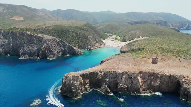 Boat Sails out Blue Cove at Cala Domestica Beach, Italy - 4k Aerial Circling