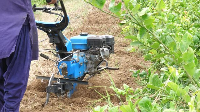 Pakistani Farmer Pushing Petrol Tiller Cultivator Over Soil In Sindh, Pakistan. Slow Motion