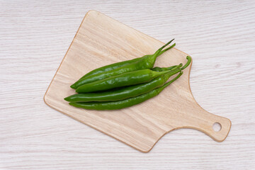 Fresh green chillies plated on a white background