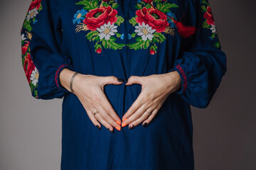 Fototapeta na wymiar Pregnant girl in a dress holds her hands on her belly 