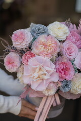 Beautiful spring flowers in box on woman hands. Preserved arrangement in grey round box. Women's day.