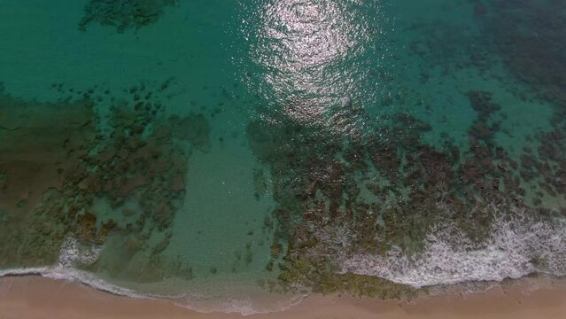 Drone tilt up over pristine Amami Beach (Japan) reveals turquoise ocean and reef