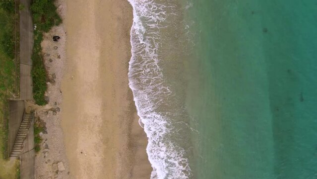 Gentle waves crashing onto pristine Amami beach, Japan - aerial top down