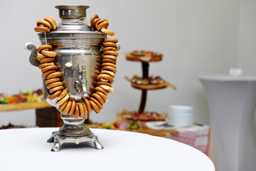 Traditional Russian samovar with a bunch of bagels in white, light room