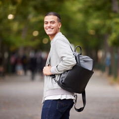 Student portrait and university man travel commute in park with backpack and optimistic smile. Happy, youth and gen z college learner smiling while commuting in New York, USA with bokeh lights
