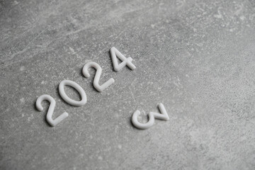 Fototapeta premium Year 2024 laid out in white numbers gray concrete background.