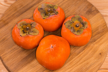 Persimmon fruits on the wooden surface close-up