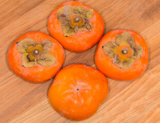 Persimmon fruits on the wooden surface, top view close-up