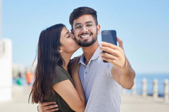 Phone, kiss or couple love taking a selfie on a romantic honeymoon, beach holiday or vacation in a summer romance. Smile, profile pictures or happy man enjoys quality bonding time with Indian partner