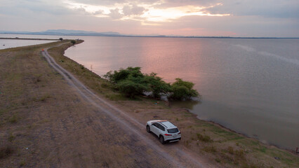 White car over the dam and large river in Pasak dam in Thailand during the rainy season with a flood pandemic.