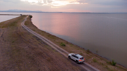 White car over the dam and large river in Pasak dam in Thailand during the rainy season with a flood pandemic.