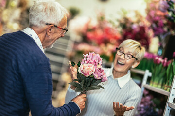 Romantic middle-aged man giving his beautiful wife flowers