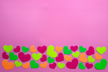 Decorative hearts. Flatlay. The concept of bright holiday, Valentines Day, birthday. Space for text. Multi-colored heart-shaped confetti lie below on a plain pink background. Top view. Copy space.