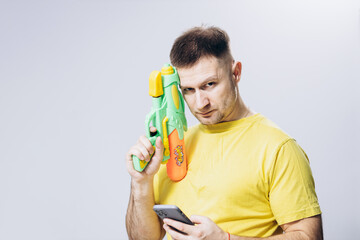 A man in a yellow T-shirt holds a water pistol in his hand. Attractive guy