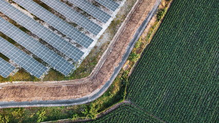 Fly over Solar cells farm beside nature green farm around large industrial factory area. Solar farms are generating renewable energy for the industry.
