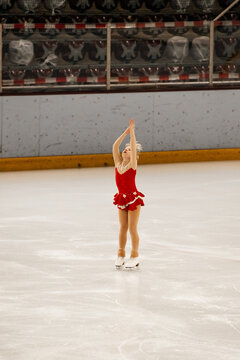 a little girl in a red dress participates in a figure skating competition	