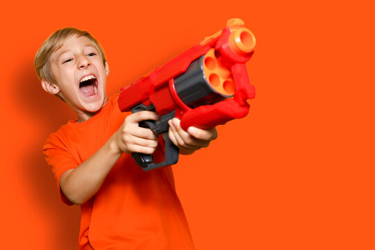 A cheerful boy with a toy gun screams
