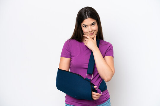 Young Brazilian woman with broken arm and wearing a sling isolated on white background thinking