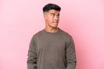 Young caucasian handsome man isolated on pink background having doubts while looking up