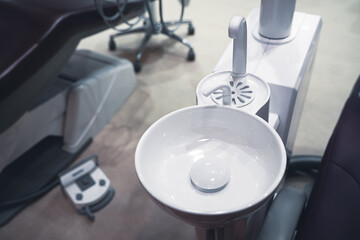 dental white ceramic spit sink near chair in dentist office