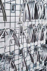 row of various stainless steel dental extraction forceps tools hanging on display