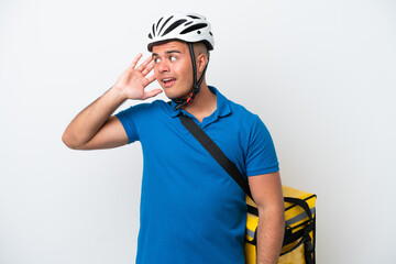 Young caucasian man with thermal backpack isolated on white background listening to something by putting hand on the ear