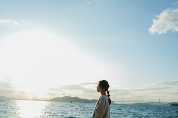 Fototapeta premium 海で夕日を見ている女性