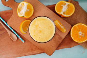 Fototapeta na wymiar Orange fruit smoothie in a glass with fresh orange slices on wood 