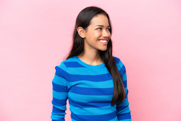 Fototapeta premium Young Colombian woman isolated on pink background looking to the side and smiling