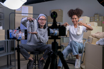 Mixed race couple of Asian man and African-American woman blogger or vlogger looking at camera...