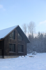 Winter's Tale. Black cottage in a beautiful snow forest. Picturesque landscape with a black wooden house in winter time.