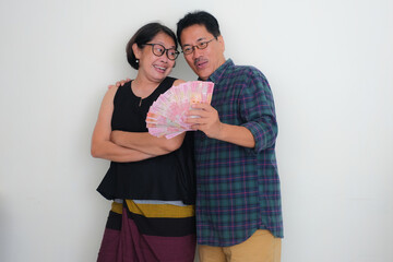 Husband and wife hugging happily with lots of money in hands