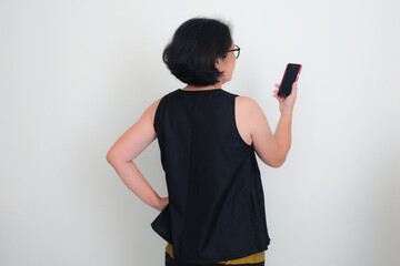 Rear view of an Asian woman standing and making a video call using smartphone in her hand