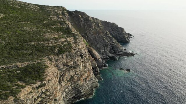 Steef cliffs and rocky coastline during twilight at La Pelosa, Sardinia - Aerial 4k