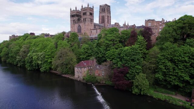 Drone shot flying up beside Durham Cathedral from the River Wear on a sunny day, County Durham, UK