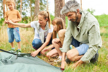 Family setting up tent for camping during vacation