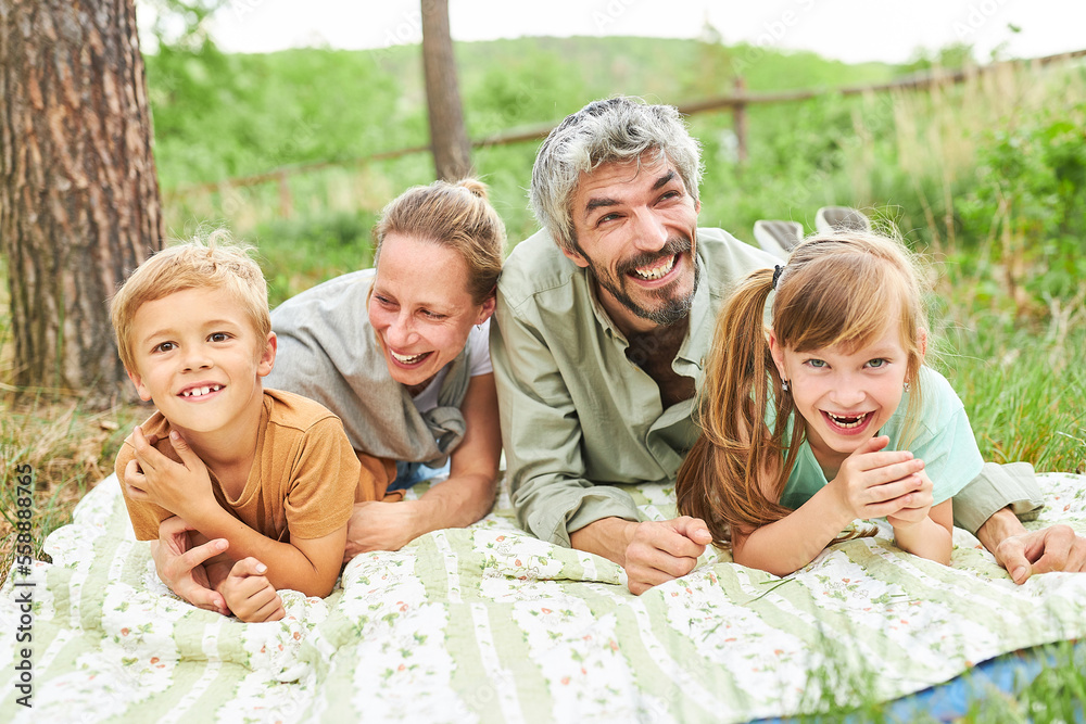 Wall mural Cheerful family lying on blanket in summer holiday