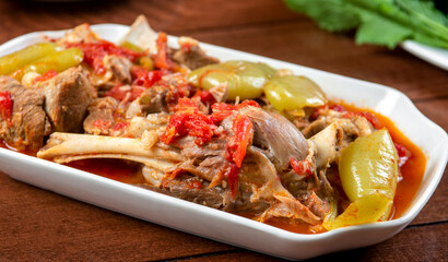 Khashlama is popular Armenian dish, which is prepared from beef with vegetables. Khashlama in the plate. stewed lamb on the bone with vegetables on wooden desk
