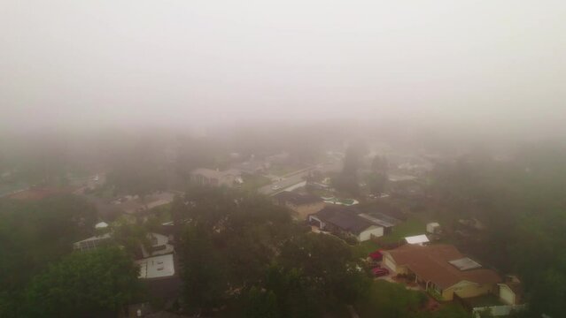 Aerial flyover through foggy and misty neighborhood in city of Ocoee, Florida with no vehicles driving  and nobody outside.  Ocoee is a family oriented town with many neighborhoods.
