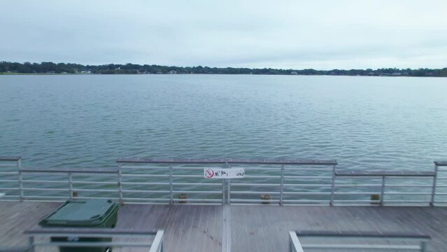 Flyover of fishing dock on Starke Lake and cloudy sky in Ocoee, Central Florida.  Ocoee is a family oriented town with restaurants, breweries, bars, and shopping.