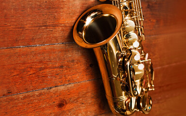 Close up of gold metal trumpet placed on brown leather case, on brown wood background.