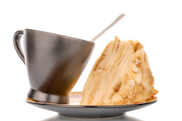 One piece of cream cake on a ceramic plate and black cup, macro, isolated on white background.